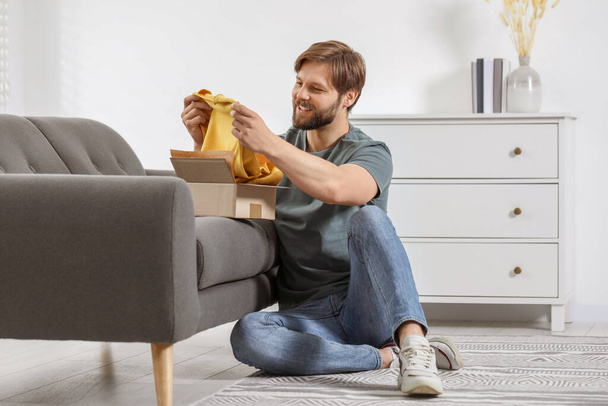 Happy man with parcel at home. Internet shopping - Fotoğraf, Görsel