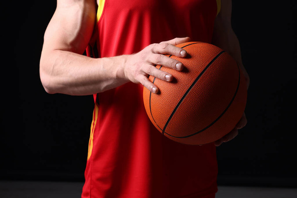 Athletic man with basketball ball on black background, closeup - Foto, Bild