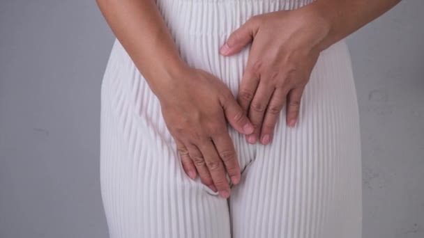 白い背景に隔離された股上に手を持つ女性。女性の手は骨盤痛や膣のかゆみで彼女の股を保持します。婦人科の問題。衛生コンセプト - 映像、動画