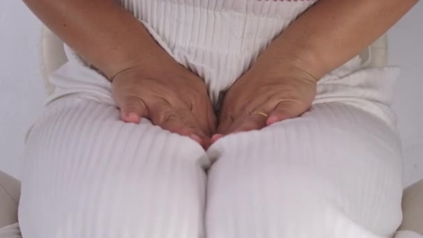 Elleri kasıklarında olan bir kadın beyaz arka planda izole edilmiş. Kadın eli kasığını pelvis ağrısı ya da vajinal kaşıntıyla tutuyor. Jinekolojik sorunlar. Sağlık hijyeni kavramı - Video, Çekim