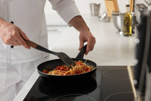 Professional chef cooking delicious pasta on stove in kitchen, closeup - Foto, imagen