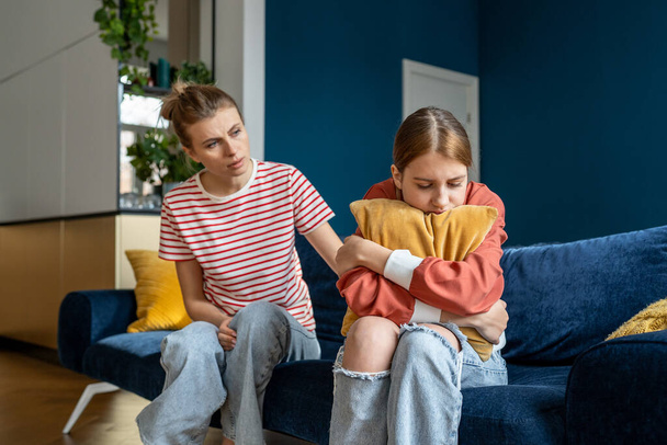 Mother supporting child upset teen girl during difficult adolescence stage, loving parent comforting child at home. Sad teenage daughter crying and feel anxious, being bullied at school - Foto, Bild