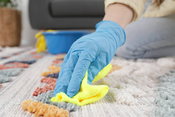 Woman in rubber gloves cleaning carpet with rag indoors, closeup - Foto, imagen