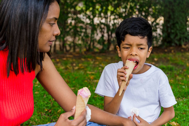 Мати і син насолоджуються морозивом разом на відкритому повітрі в парку. Концепція сім'ї, їжі та літа
. - Фото, зображення