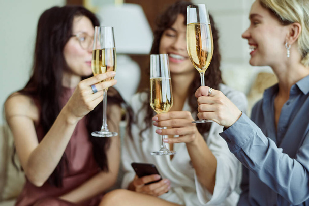 Drei glückliche Mädchen mit Champagner feiern die bevorstehende Hochzeit eines von ihnen, während sie Flöten in der Hand halten und auf der Junggesellenparty anstoßen - Foto, Bild