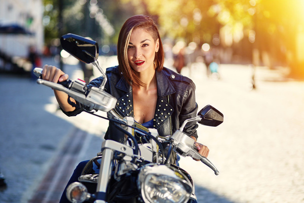 Menina motociclista em uma jaqueta de couro em uma motocicleta
 - Foto, Imagem
