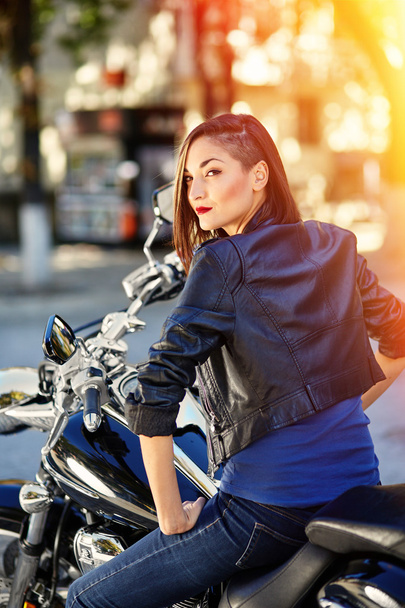 Ποδηλάτης κορίτσι σε ένα δερμάτινο σακάκι με μοτοσικλέτα - Φωτογραφία, εικόνα