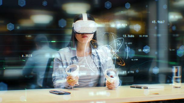 Kancelářská pracovnice používá soupravu VR a bezdrátové ovladače, sleduje data a čísla ve 3D virtuální realitě. Asijka pracuje v moderní hi-tech IT společnosti. Budoucí inovativní digitální technologie. - Fotografie, Obrázek
