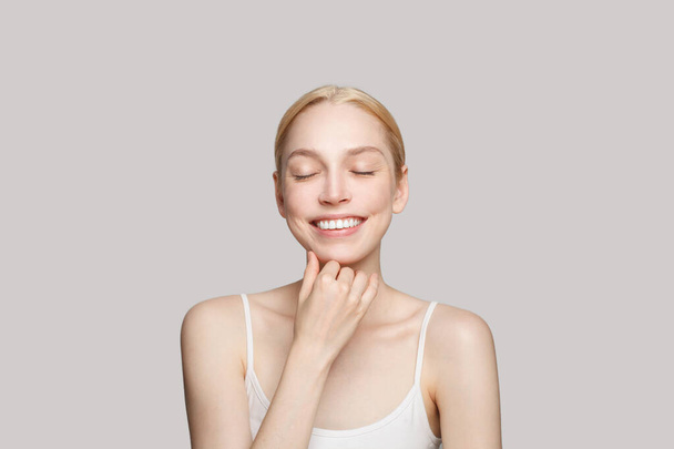Giovane donna adulta sorridente con pelle chiara e trucco naturale. Trattamento viso, cura della pelle e concetto di cosmetologia - Foto, immagini