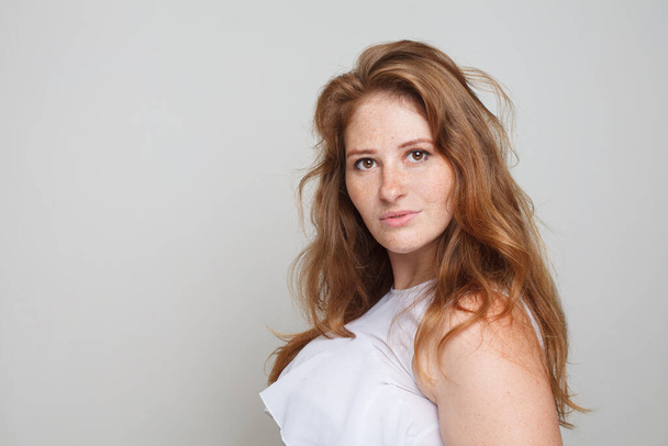 Nice redhead model woman with wavy hair looking at camera on white background - Zdjęcie, obraz