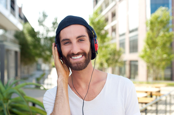 Веселий молодий чоловік з навушниками на відкритому повітрі
 - Фото, зображення