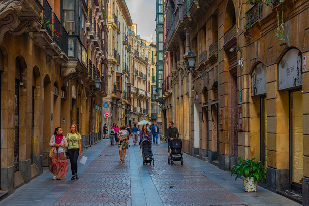 Bilbao, Spain, June 2, 2022: People are strolling through a narrow street of the old town of Bilbao, Spain. - Photo, Image