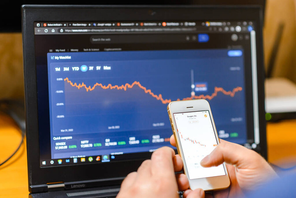 スマートフォンやノートパソコンの画面で株式市場をチェックするビジネスマン金融株式市場の取引データチャートを分析する画面貿易と金融の概念. Telsiai,リトアニア. 03-30-2023 - 写真・画像