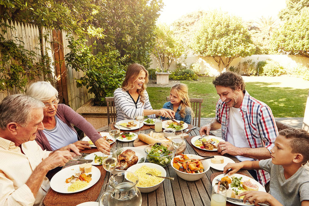 Kiedy dzielisz się jedzeniem, dzielisz się szczęściem. rodzina jedząca razem lunch na świeżym powietrzu - Zdjęcie, obraz