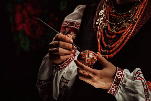 Ukrainian woman painting traditional ornamets on Easter egg - pysanka. Artist working in national costume. Preparation for Christian holiday.  - Fotografie, Obrázek