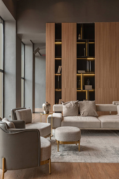 living room, marble wall fireplace and stylish bookcase in chic expensive interior of luxury country house with a modern design with wood and led light, gray furniture with gold elements - Фото, зображення
