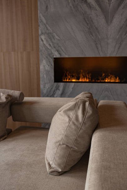 living room, marble wall fireplace and stylish bookcase in chic expensive interior of luxury country house with a modern design with wood and led light, gray furniture with gold elements - Zdjęcie, obraz