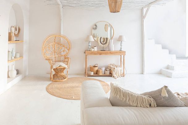 Cozy interior of a bright Balinese-style apartment with white walls, bamboo chair, big white sofa and decorations - Φωτογραφία, εικόνα