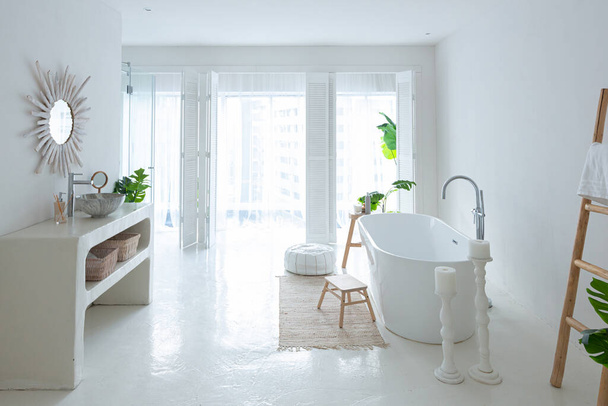 Extra white and very light minimalistic stylish elegant interior of bathroom with modern bath, green plants and wooden elements - Foto, Imagen