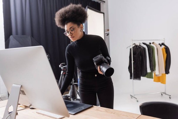 afro-amerikai tartalom menedzser áll digitális fényképezőgép közelében számítógép monitor fotó stúdió - Fotó, kép