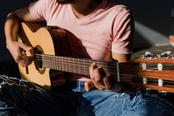 Λατέν άνθρωπος παίζει ακουστική κιθάρα κάθεται στο πάτωμα στο σαλόνι στο Sunny σκληρό φως στο Stylish Loft Apartment στο Μεξικό Λατινική Αμερική, ισπανόφωνοι άνθρωποι - Φωτογραφία, εικόνα