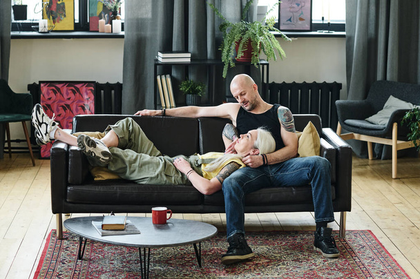 Tatuaż Dojrzałe biały mężczyzna i kobieta w miłości noszenie casual ubrania relaks razem na kanapie w poddaszu salon w domu - Zdjęcie, obraz
