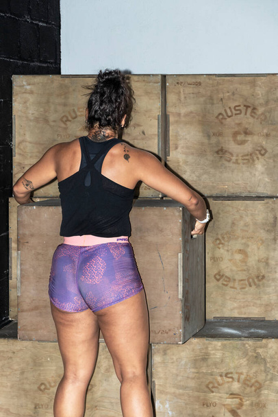 Determinación en movimiento: Una mujer latina viaja moviendo cajas en el gimnasio - Foto, Imagen