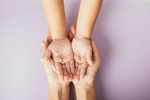 Closeup top view family hands stack palms studio shot isolated on purple background, parents and kid holding empty free space on hand together, Gesture sign of support and love, Family and parents day - Фото, зображення