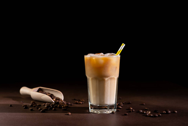 Cappuccino with Ice cubes in a tall Glass against a black background. Iced Coffee with milk in a glass - Photo, Image