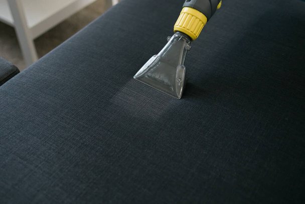 Man in protective rubber glove cleaning sofa with professionally extraction method with washing vacuum cleaner. Early spring regular cleanup. Commercial cleaning company - Φωτογραφία, εικόνα