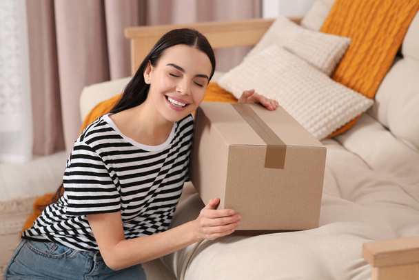 Happy young woman with parcel at home. Internet shopping - Фото, зображення