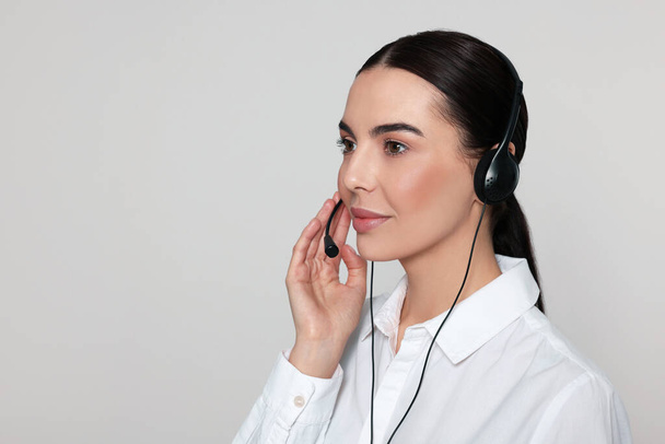 Hotline operator with modern headset on light grey background, space for text. Customer support - Foto, immagini