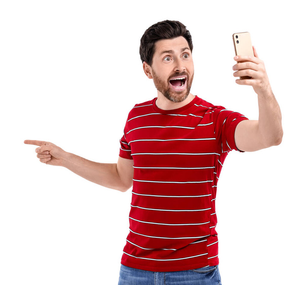 Emotional man taking selfie with smartphone on white background - Zdjęcie, obraz