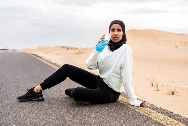 Beautiful middle-eastern arab woman wearing hijab training outdoors in a desert area - Sportive athletic muslim adult female wearing burkini sportswear doing fitness workout - Photo, Image