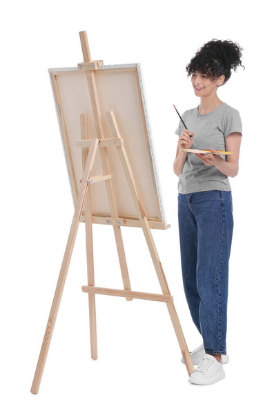 Jeune femme peignant sur chevalet avec toile sur fond blanc - Photo, image