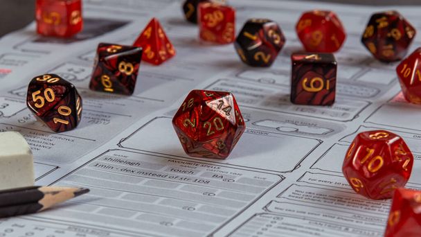 Крупный план набора красных RPG игровых кубиков на листе символов - Фото, изображение