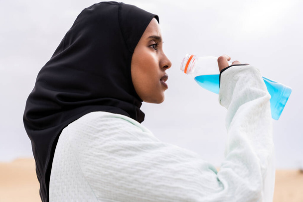 Piękna arabka z Bliskiego Wschodu w hidżabie trenująca na świeżym powietrzu na pustyni - Sportowa muzułmanka muzułmańska dorosła kobieta ubrana w strój sportowy burkini wykonująca trening fitness - Zdjęcie, obraz