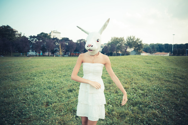 konijn masker absurd mooie jonge vrouw met witte jurk - Foto, afbeelding