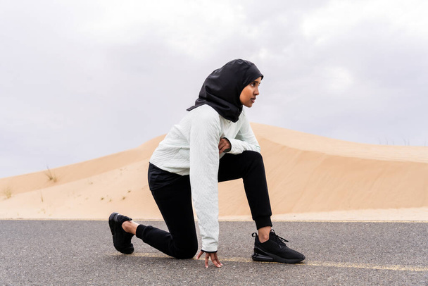 Bella donna araba medio-orientale che indossa allenamento hijab all'aperto in una zona desertica - Sportiva donna musulmana adulta atletica che indossa abbigliamento sportivo burkini facendo allenamento di fitness - Foto, immagini