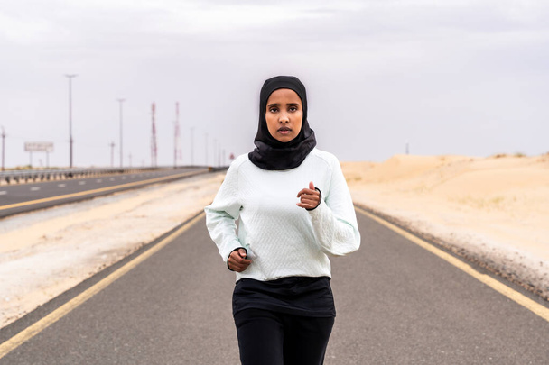 Beautiful middle-eastern arab woman wearing hijab training outdoors in a desert area - Sportive athletic muslim adult female wearing burkini sportswear doing fitness workout - Foto, immagini