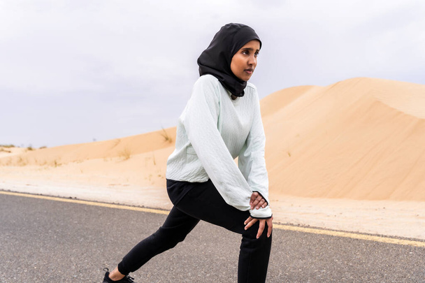 Beautiful middle-eastern arab woman wearing hijab training outdoors in a desert area - Sportive athletic muslim adult female wearing burkini sportswear doing fitness workout - Fotoğraf, Görsel