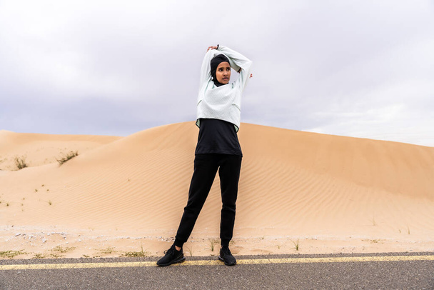 Beautiful middle-eastern arab woman wearing hijab training outdoors in a desert area - Sportive athletic muslim adult female wearing burkini sportswear doing fitness workout - Zdjęcie, obraz