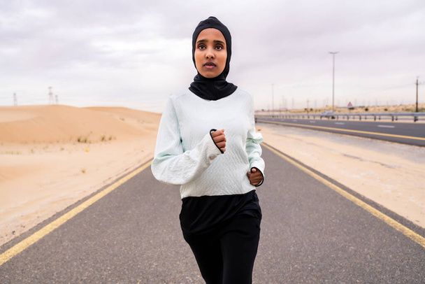 Beautiful middle-eastern arab woman wearing hijab training outdoors in a desert area - Sportive athletic muslim adult female wearing burkini sportswear doing fitness workout - Foto, Imagem