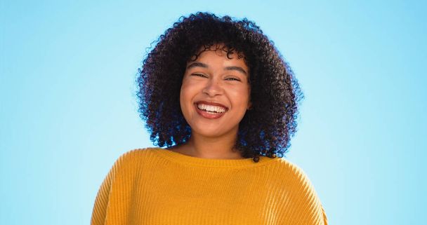 Face, funny and black woman with smile, excited and cheerful against a blue studio background. Portrait, African American female and lady with freedom, laughing and carefree with happiness and joyful. - Photo, Image