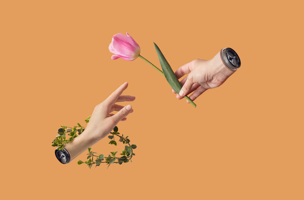 Ein kreatives Konzept von Hand mit Roboterteilen aus Metall, die eine rosa Tulpe und einen grünen Zweig vor pastellorangefarbenem Hintergrund halten. Eine minimale metastasierende Idee. - Foto, Bild