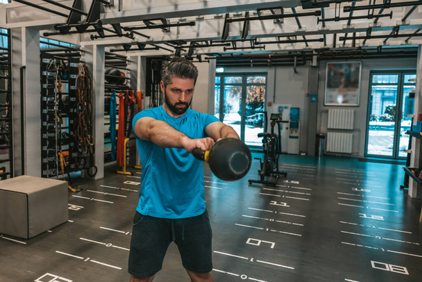 Workout. Young bearded man having a workout in gym - Φωτογραφία, εικόνα