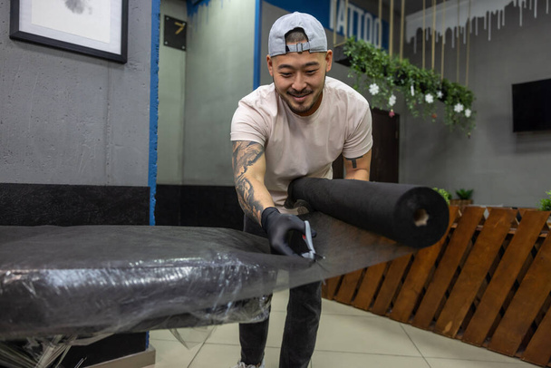 In the tattoo salon. Asian tattoo master preparing couch for tattoo session - Valokuva, kuva