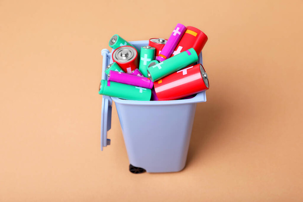Many used batteries in recycling bin on light brown background - Fotografie, Obrázek