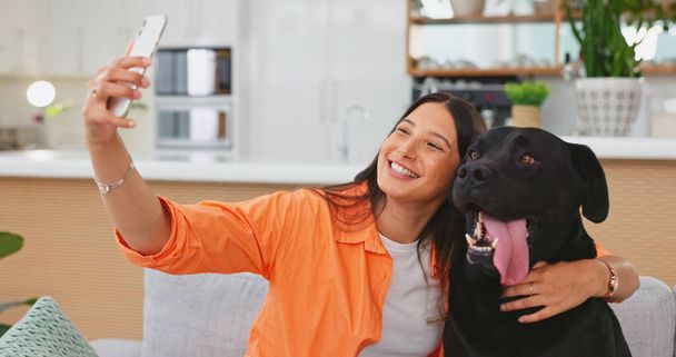 Woman, dog and selfie on living room sofa in home for care hug, touch and embrace for happy friends. Doggy mom, couch and lounge for pet, animal or social media app with smile, relax and photography. - Foto, Imagen