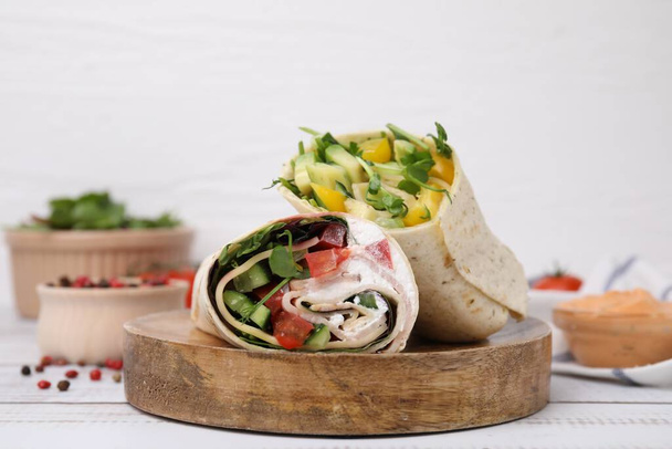 Delicious sandwich wraps with fresh vegetables and peppercorns on white wooden table - Foto, Imagem